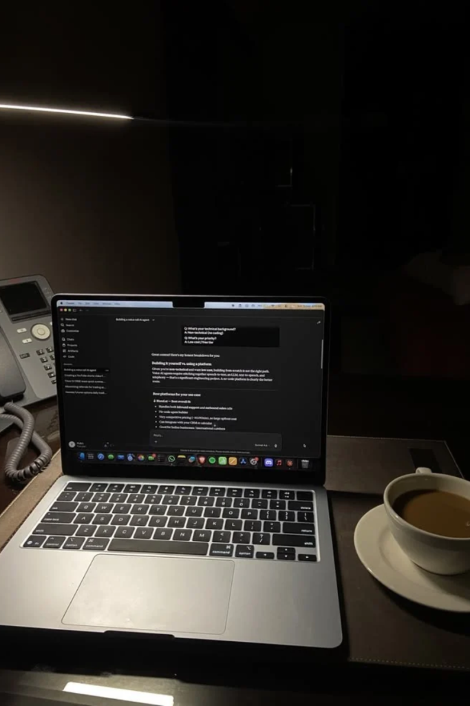 A laptop displaying a ChatGPT chat interface with dark mode enabled next to a white cup of coffee on a desk in low warm lighting.