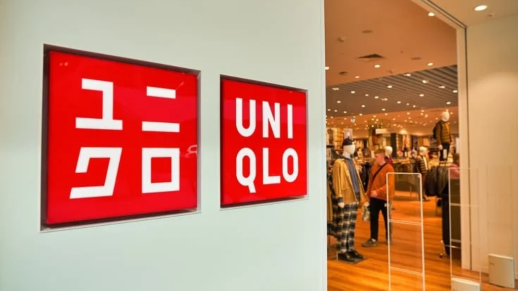 Interior view of a modern, minimalist Uniqlo retail store featuring clean aisles, structured clothing displays, and neutral lighting.